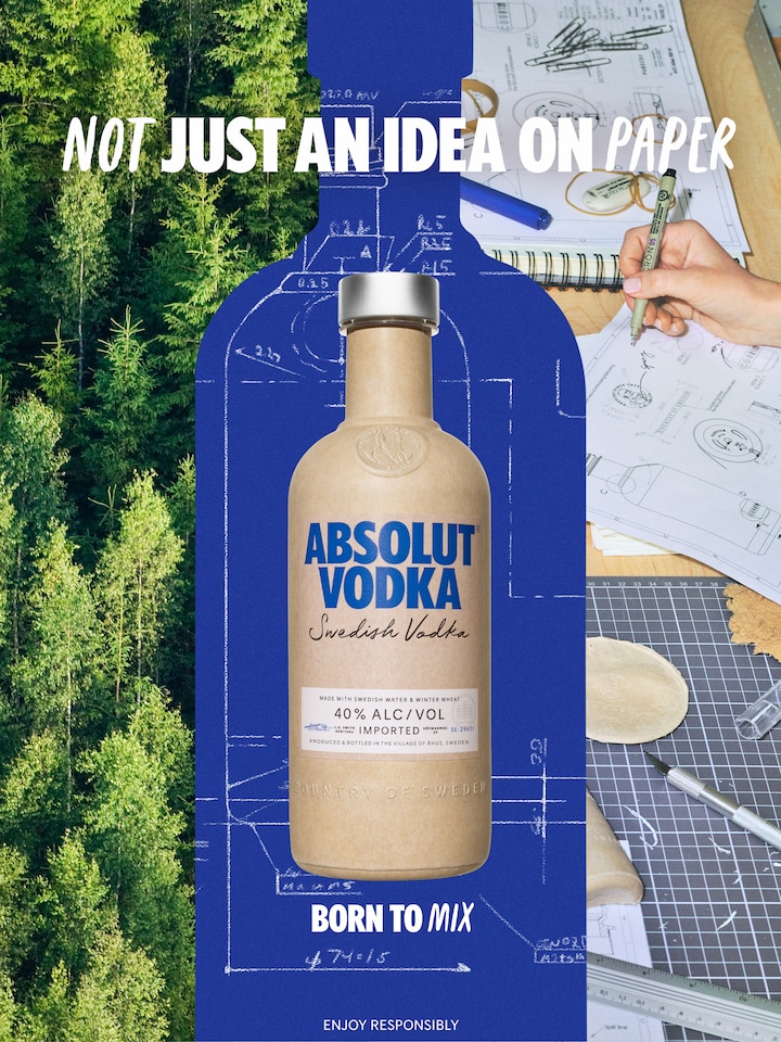 a cardboard bottle and behind it a table with sketches and the text not just an idea on paper